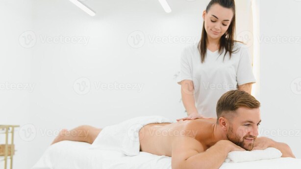 A massage therapy session in a spa setting with a client lying face down on a massage table and a therapist standing behind. - Male Massage therapist for colombo with A/C comfortable room (Colombo)