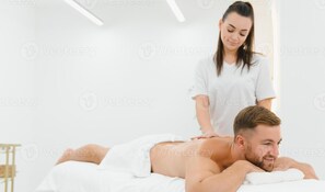 A massage therapy session in a spa setting with a client lying face down on a massage table and a therapist standing behind. - Male Massage therapist for colombo with A/C comfortable room (Colombo)