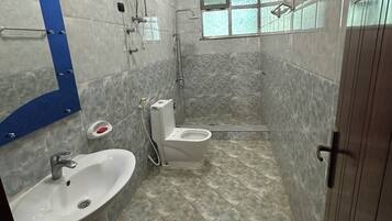 Uma casa de banho com lavatório, sanita e chuveiro.