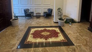 A spacious lobby with a patterned carpet, potted plants, and modern lighting. - Private room with private bathroom and closet.. shared living room and kitchen (Addis Ababa)