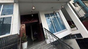 A multi-story building with a prominent entrance, a staircase, and a balcony with a metal railing. - Private room with private bathroom and closet.. shared living room and kitchen (Addis Ababa)