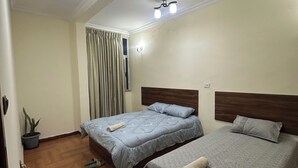 A hotel room with two beds, a ceiling fan, a potted plant, and a window with curtains. - Private room with private bathroom and closet.. shared living room and kitchen (Addis Ababa)