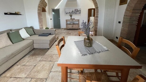 A dining area with a table and chairs, a sofa, and an arched doorway leading to another room. - Relaxation in the Tuscan hills Typical Tuscan farmhouse, app.MIELE (Collesalvetti)