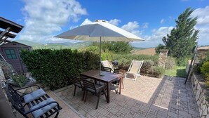A patio with a table and chairs, a grill, and a large umbrella. - Relaxation in the Tuscan hills Typical Tuscan farmhouse, app.MIELE (Collesalvetti)