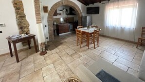 A spacious living area with a stone floor, wooden furniture, and a kitchen in the background. - Relaxation in the Tuscan hills Typical Tuscan farmhouse, app.MIELE (Collesalvetti)
