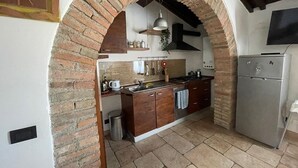 A kitchen with an arched brick entrance, wooden cabinets, a stainless steel sink, and a built-in oven. - Relaxation in the Tuscan hills Typical Tuscan farmhouse, app.MIELE (Collesalvetti)