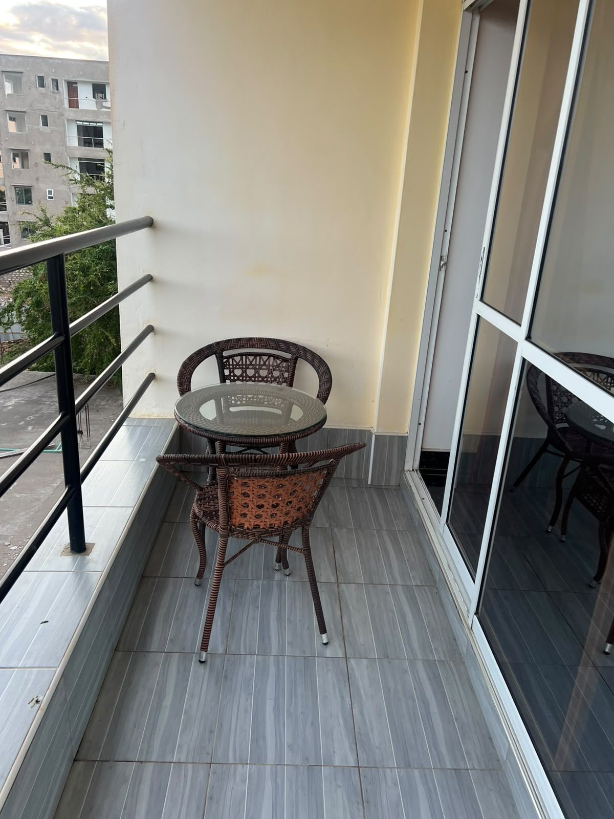 A balcony with a glass door, a round table with chairs, and a railing.