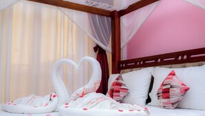 Una cama con dosel, almohadas blancas y una disposición decorativa de toallas.