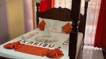 A bed with a canopy, a neatly made bedspread, and a towel with the name 'VIDZO' on it.