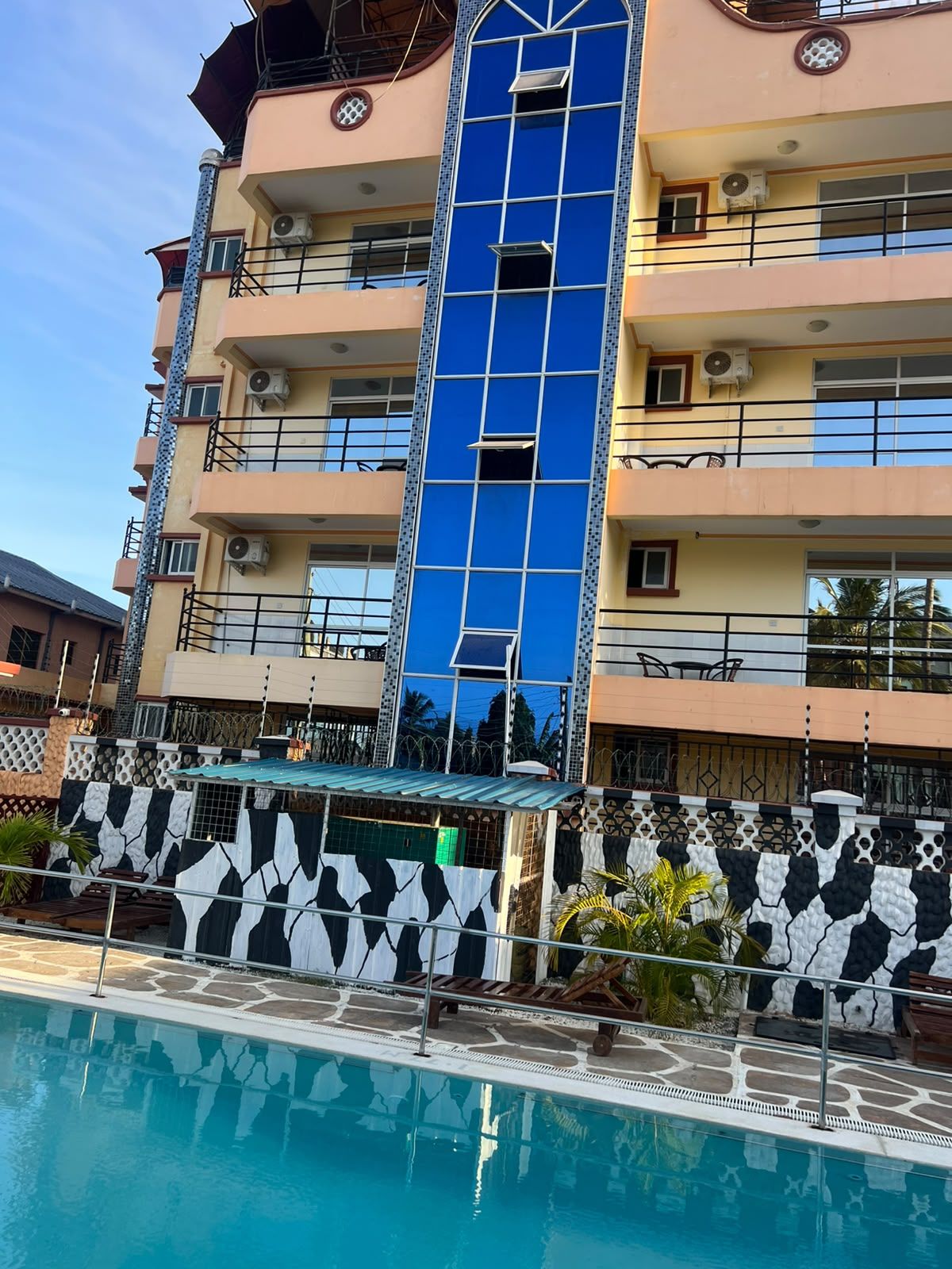 A multi-story hotel with a swimming pool in the foreground.