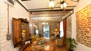 Un rincón comedor acogedor con una mesa y sillas de madera, pared de ladrillo y una lámpara colgante.