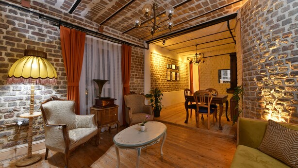 Una habitación acogedora con pared de ladrillo, suelo de madera, una mesa redonda, dos sillas, un sofá y una lámpara.