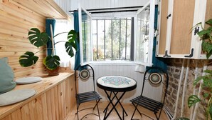 Una habitación pequeña y acogedora con un banco de madera, una mesa redonda con encimera de mosaico y dos sillas.