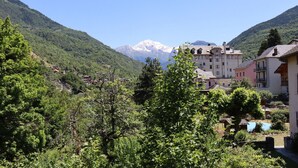 Un pueblo montañoso con edificios tradicionales y un pico nevado destacado al fondo.