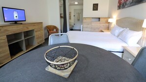 Habitación de hotel con cama, televisor, mesa de comedor y un cuenco decorativo, además de un cuadro en la pared.