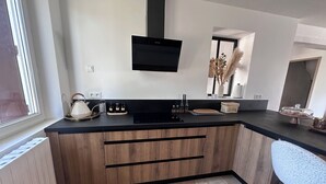 Eine moderne Küche mit schwarzem Arbeitsplatz, Holzschränken, integriertem Backofen und einem Flachbildfernseher.