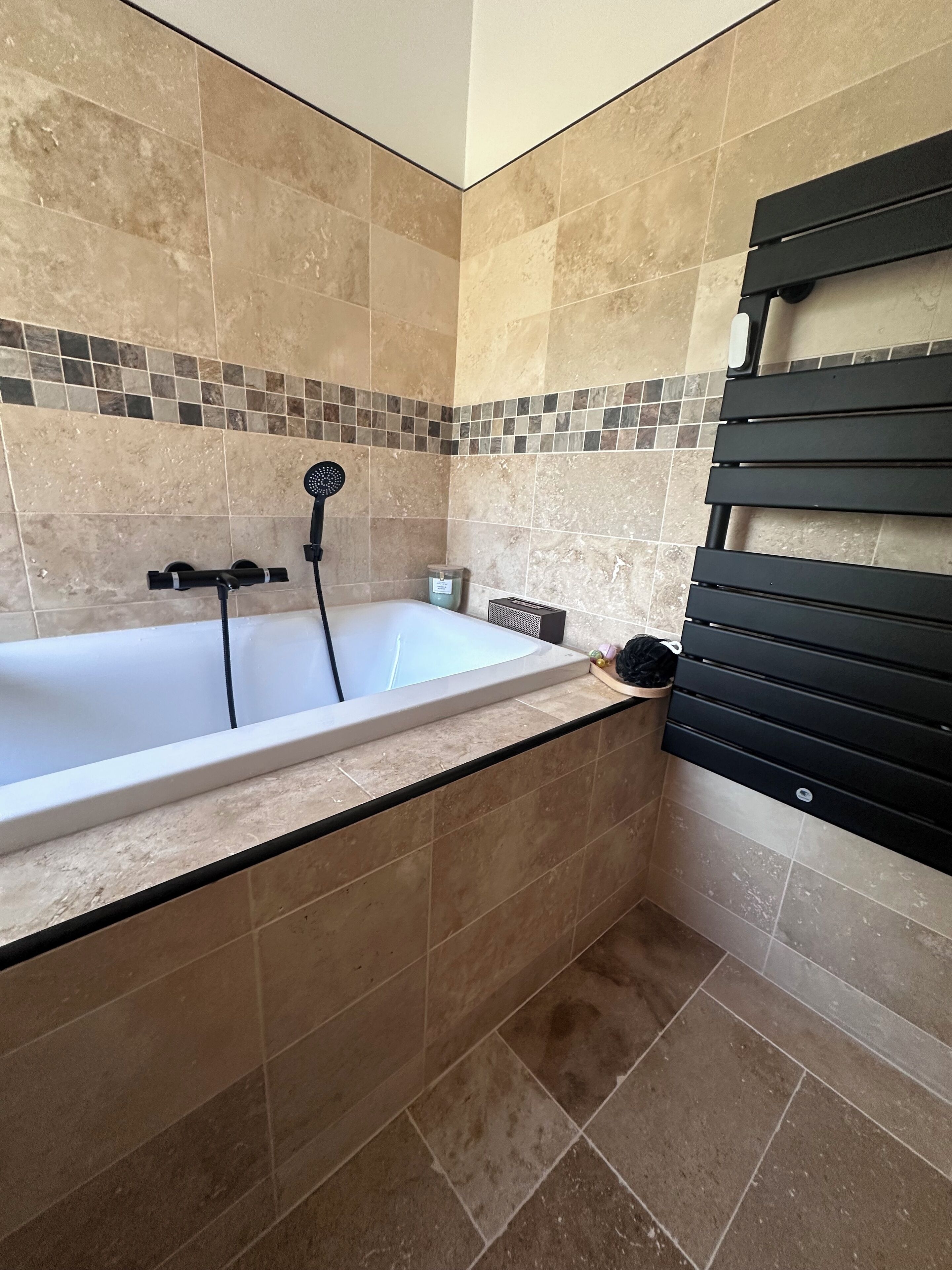 A bathroom with a bathtub, a showerhead, and a towel rack.