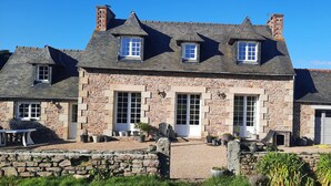 A stone house with multiple windows, a stone wall in front, and potted plants. - A beautiful, charming Breton home. Located in Paimpol, 1 km from the mer.Au —quiet and private. (Paimpol)