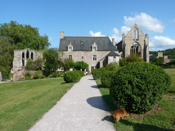 Un bâtiment historique en pierre, avec un chemin pavé menant à l’entrée.