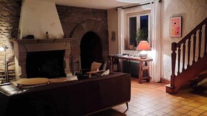 A cozy living room with a fireplace, a wooden staircase, and a tiled floor. - A beautiful, charming Breton home. Located in Paimpol, 1 km from the mer.Au —quiet and private. (Paimpol)