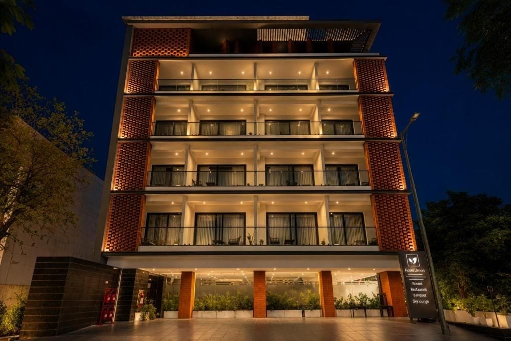 Un hotel moderno a più piani, con balconi su ogni piano, un ingresso ben illuminato e una segnaletica che indica servizi come camere, un ristorante e un lounge panoramico.