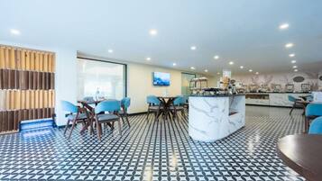 Un intérieur moderne avec un sol à motifs, un espace de repas central doté de chaises et une cuisine avec un îlot en marbre.