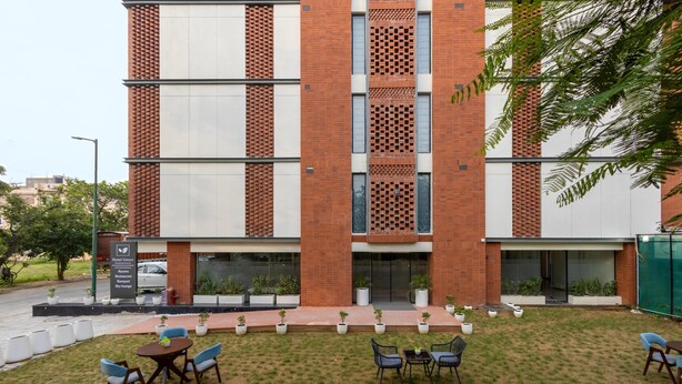 Um hotel com fachada de tijolos moderna, área de estar externa e placa indicando comodidades como lounge e lounge no terraço.