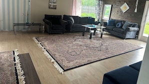 Ein Wohnzimmer mit großem Teppich, zwei Sofas, einem Couchtisch und einem Fernseher.
