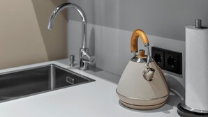 A kitchen with a modern faucet, a kettle, and a paper towel dispenser. - Apartment 2 Plum (Lüneburg)