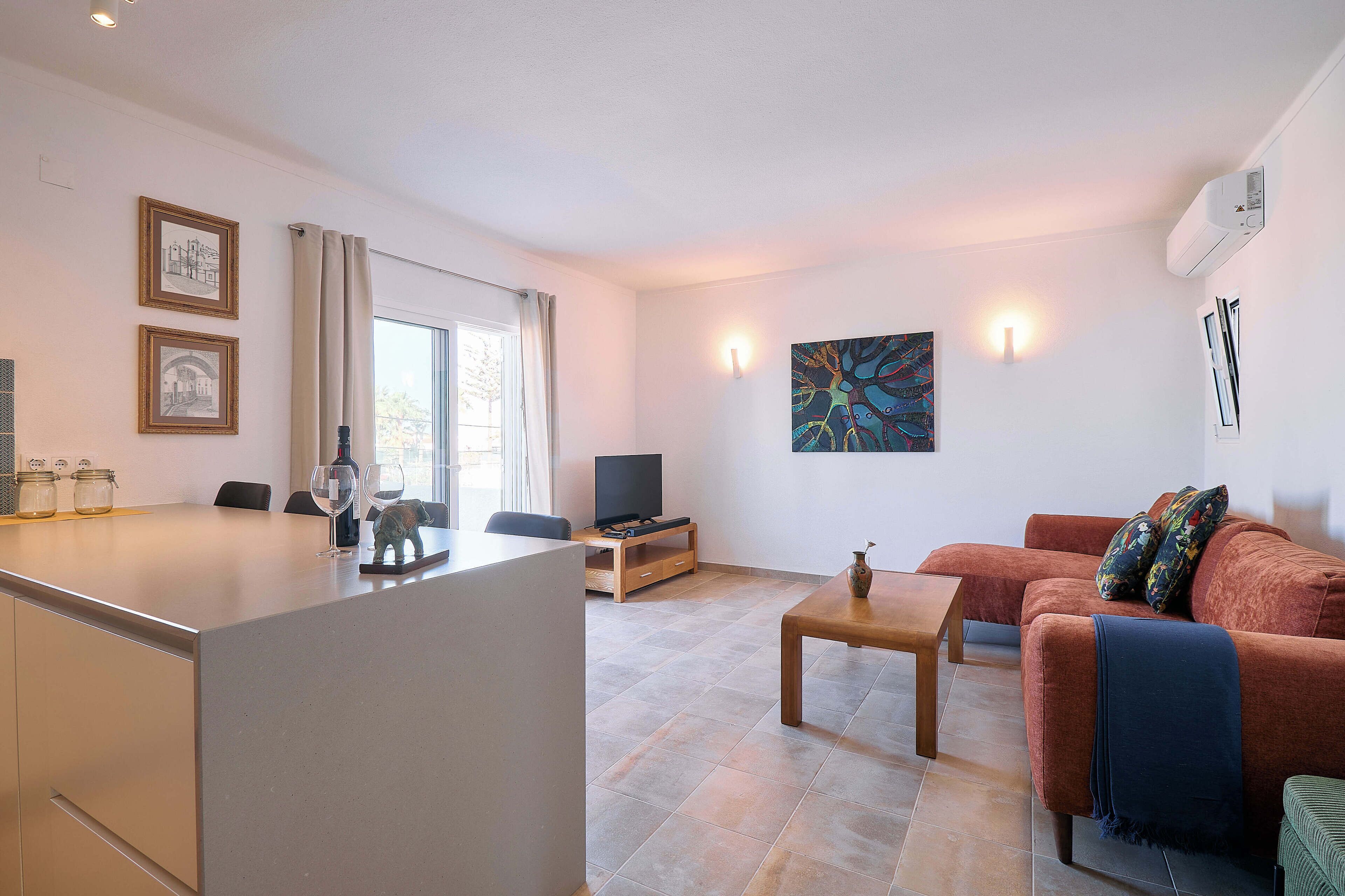 Ein modernes Wohnzimmer mit einer Couch, einem Couchtisch und einem Fernseher. Es gibt einen Essbereich mit Tisch und Stühlen.