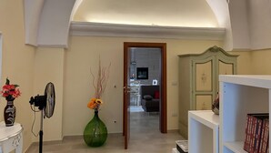 A hallway with an arched ceiling, a green vase with flowers, a fan, and a bookshelf with books. - CASA ROSALBA Typical southern house with vaulted roof a few miles from the beautiful (Taranto)