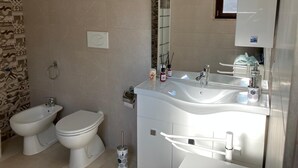 A modern bathroom with a bidet, toilet, and a large mirror above the sink. - CASA ROSALBA Typical southern house with vaulted roof a few miles from the beautiful (Taranto)
