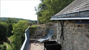 A balcony with wicker furniture and a view of a forested valley.