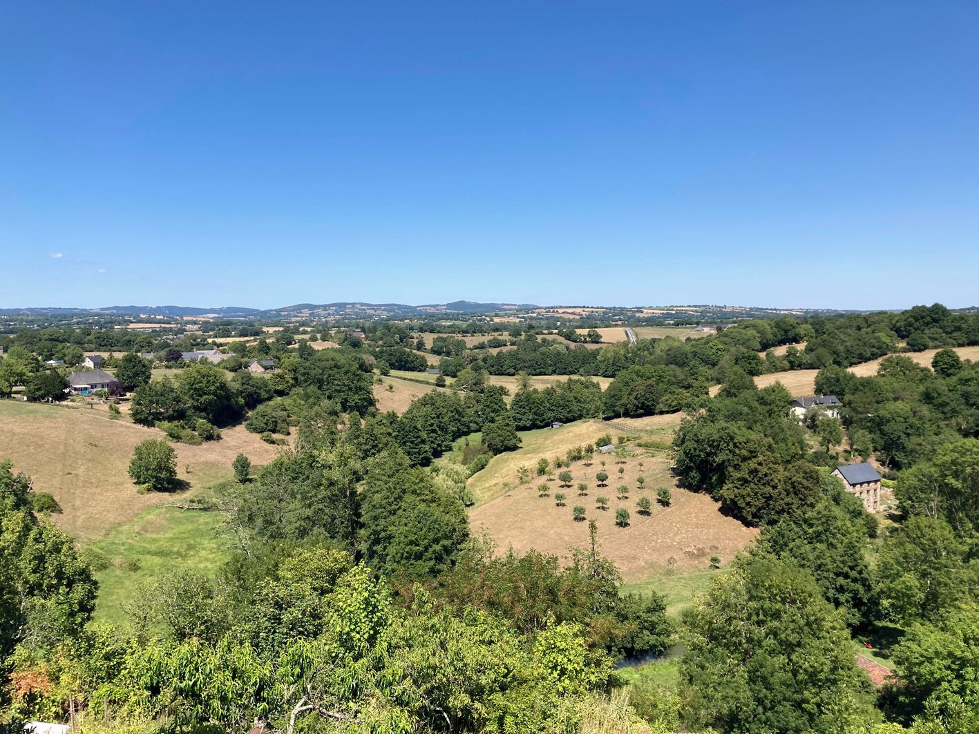 Un paysage rural parsemé de maisons, avec une végétation luxuriante et des collines douces.