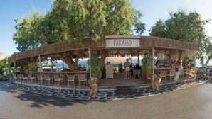 Ein Restaurant am Strand namens "PARAISO" mit Außenbereich, einem gepflasterten Bereich und Meerblick.