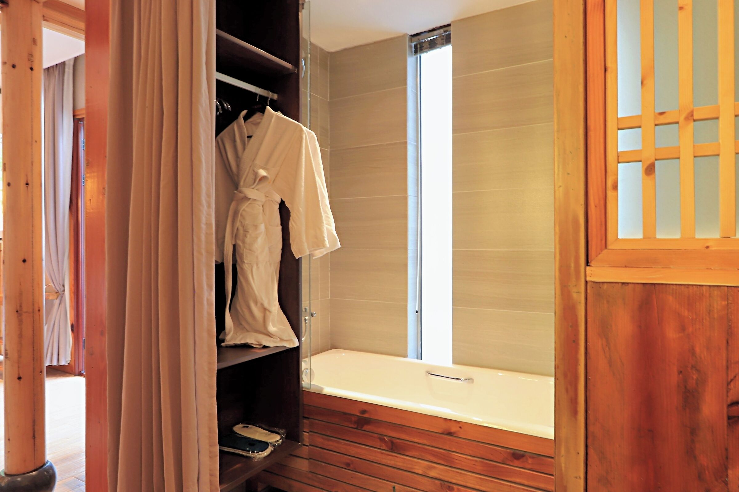 Un dressing accessible sans porte, avec des étagères en bois, un porte-manteau et une baignoire.