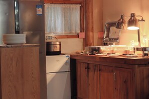 Una cocina con armarios de madera, un refrigerador de acero inoxidable, una estufa y un lavamanos.