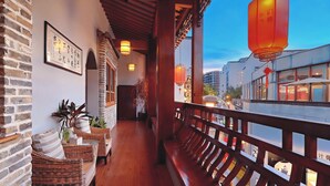 A corridor with wicker furniture, a wooden bench, and traditional lanterns. - Mild Spring Boutique Hotel (Huangshan)