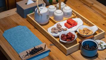 A wooden tray with tea utensils, a tissue box, and various snacks.