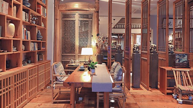 A traditional Japanese-style room with a wooden table, chairs, and a bookshelf filled with books and decorative items. - Mild Spring Boutique Hotel (Huangshan)