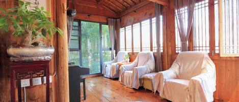 A traditional wooden interior with tatami mats, a tatami mat table, a sofa, and a potted plant.