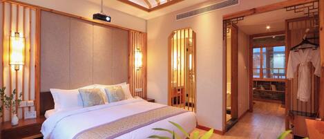 A hotel room with a large bed, wooden headboard, bedside tables, a mirror, and a hanging robe.