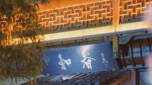 A traditional building with a tiled roof and wooden lattice windows. There are red banners hanging on the entrance. - Mild Spring Boutique Hotel (Huangshan)