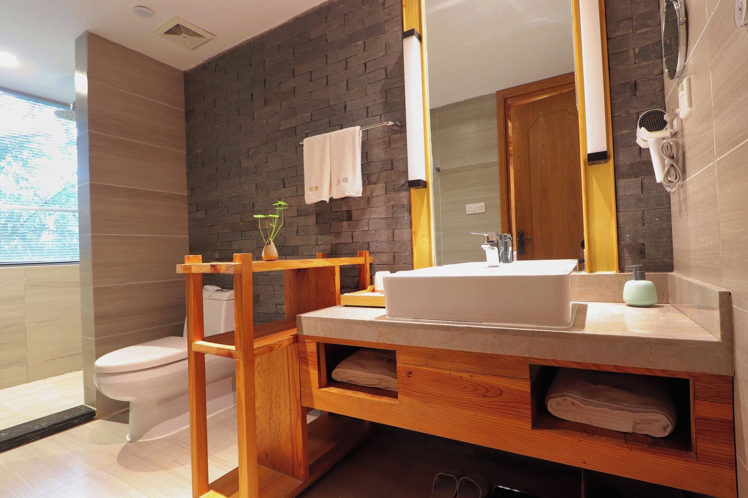 Un baño moderno con un espejo grande, tocador de madera y un inodoro.