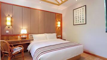 A hotel room with a large bed, bedside lamps, a desk, and a chair.