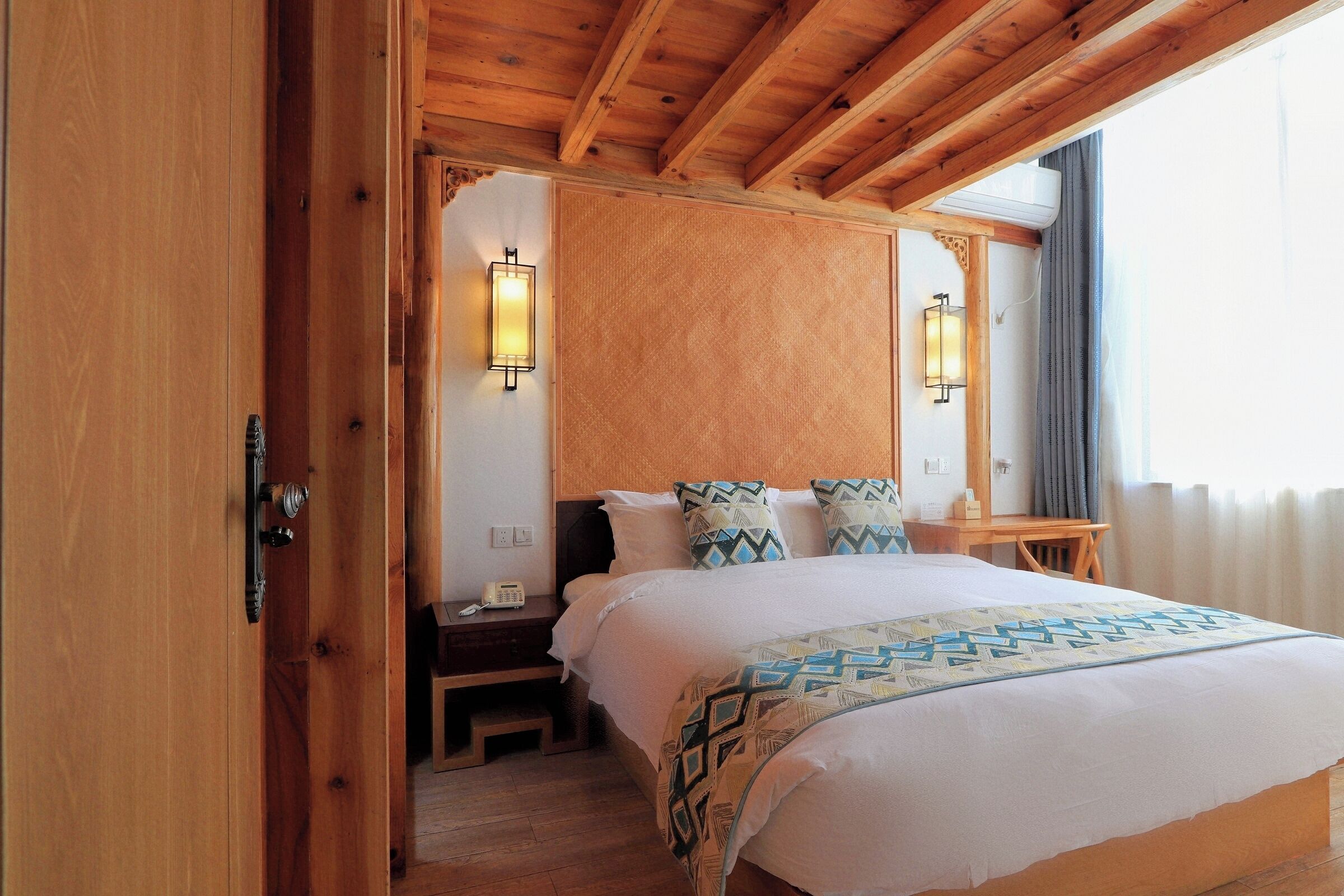 A wooden-framed bedroom with a bed, two wall-mounted lamps, and a nightstand.