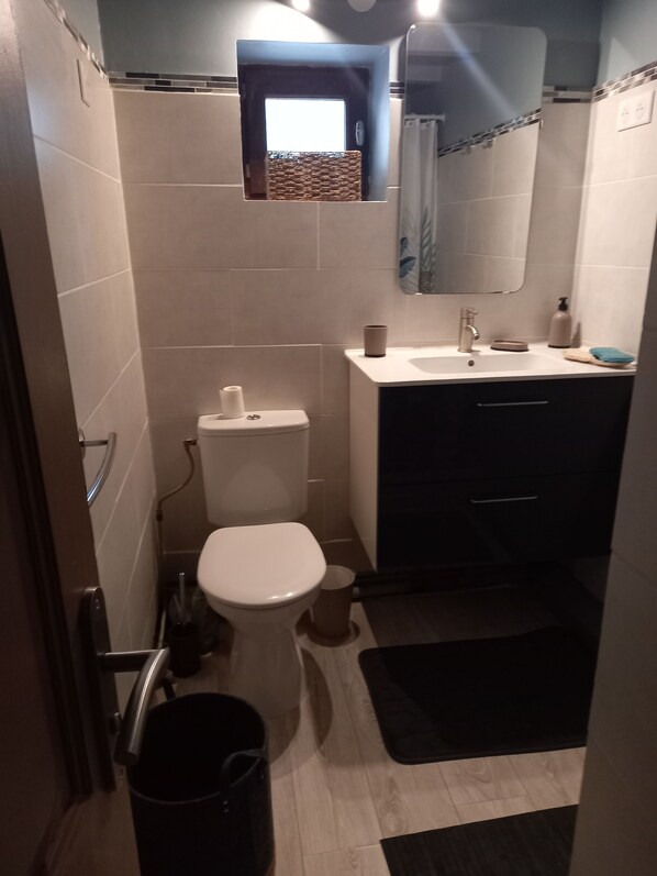 A compact bathroom with a toilet, sink, and mirror.