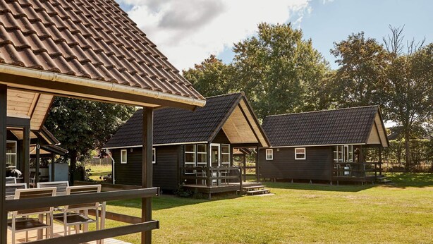 A rustic cabin-style building with a sloped roof and a wooden deck. - 6 Person Holiday Park Home in Bryrup (Bryrup)