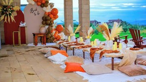 A decorated outdoor area with a 'Bride to be' sign, tables set with candles, and a view of the landscape.