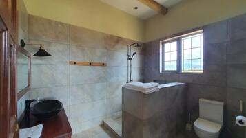 Een badkamer met douche, toilet en wastafel.